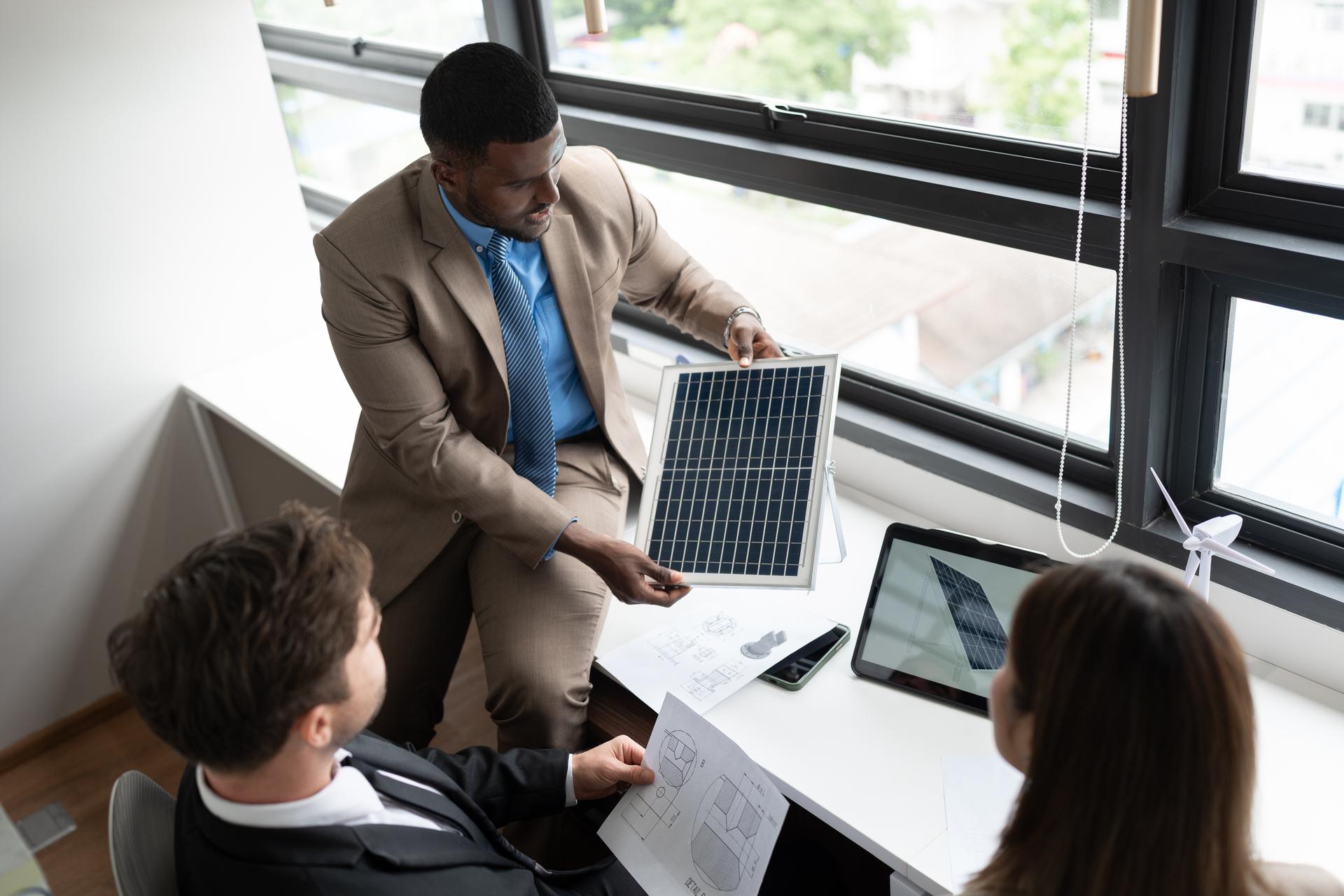 African American businessman and team business working with solar panel and tablet computer at office